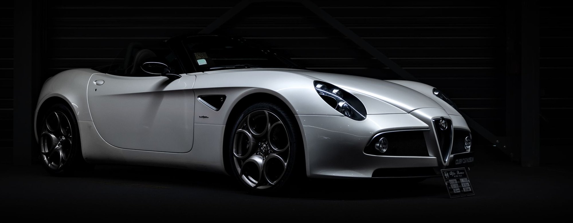 A silver sports car in a dark garage